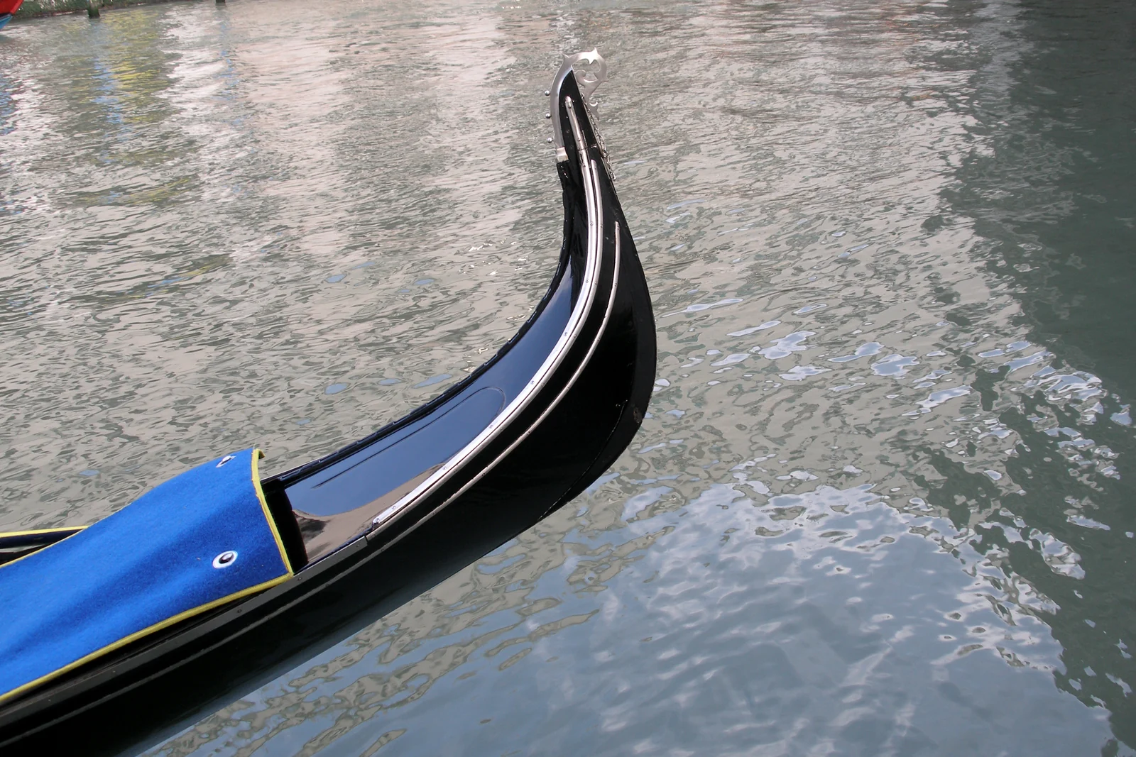 The bow of a Venetian gondola on canal water in Venice